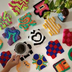 a person holding a coffee cup in front of some crocheted objects