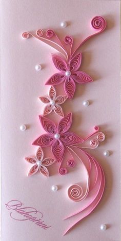 a card with pink paper flowers and pearls on the bottom, in front of a white background