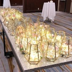 a long table topped with lots of glass vases filled with flowers on top of it