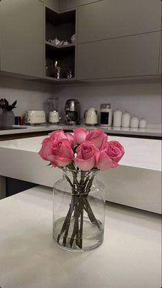 a vase filled with pink roses on top of a counter