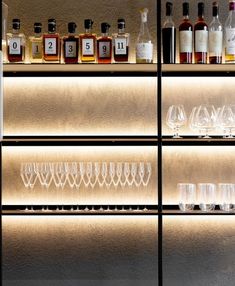 bottles and glasses are lined up on the shelves