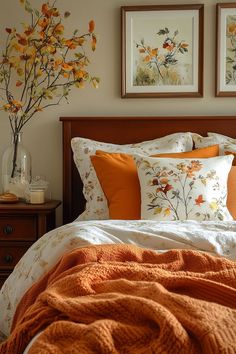 a bed with two framed pictures above it and an orange blanket on top of it