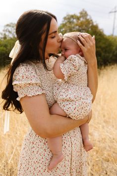 a woman holding a baby in her arms and kissing it's face with the other hand