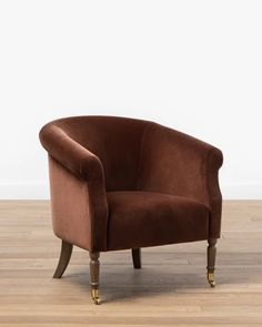 a brown chair sitting on top of a hard wood floor next to a white wall