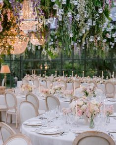 the tables are set with white linens and floral centerpieces hanging from the ceiling