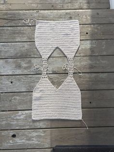 a crocheted piece of clothing hanging on a wooden wall