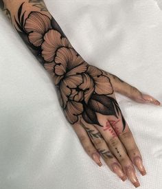 a woman's hand with black and white flowers on the left side of her arm