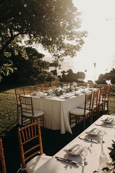 an outdoor table set up with white linens and place settings for two people to sit at