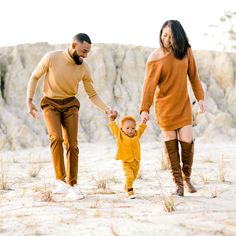 a man and woman holding hands while walking with a toddler in the desert,