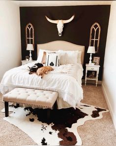 a dog laying on top of a bed in a room with cow hide rugs