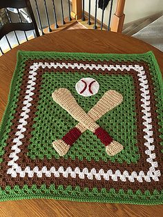 a crocheted tablecloth with baseballs and bats on it in the shape of a square