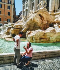 a man and woman standing next to a fountain