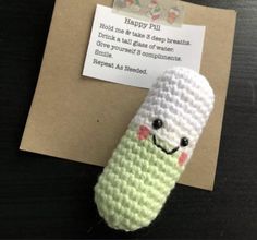 a crocheted green and white object sitting on top of a piece of paper