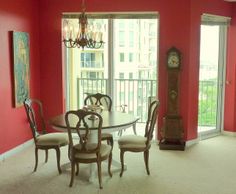 a dining room table with chairs and a grandfather clock on the wall in front of it