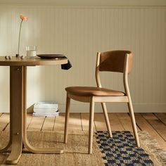 a wooden table with a plate on it and a chair next to it in front of a wall