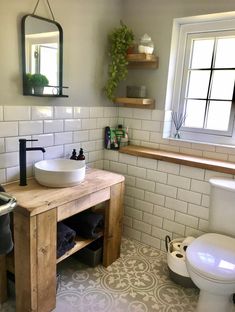 a bathroom with a sink, mirror and toilet in it's corner area next to a window