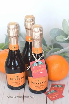 three bottles of wine sitting on top of an orange next to some cards and leaves