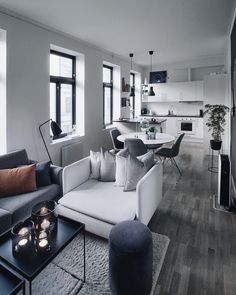 a living room filled with furniture and lots of windows next to a dining room table