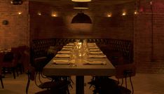 a long table is set up in the middle of a room with brick walls and exposed lighting