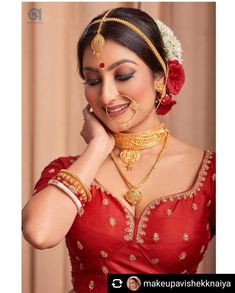 a woman in a red dress with gold jewelry on her neck and hands behind her head