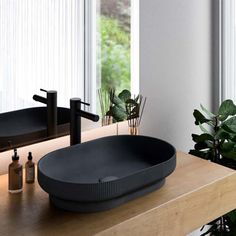 a bathroom sink sitting on top of a wooden counter next to a potted plant