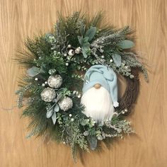 a wreath with an gnome face and greenery around it on a wooden table top