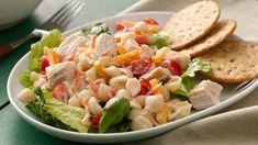 a white plate topped with pasta salad next to crackers