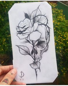 a person holding up a piece of paper with a skull and roses on it