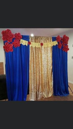 a gold and blue backdrop with red flowers on the curtain is set up for a party