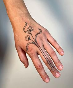 a person's hand with a flower tattoo on it