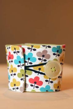 a close up of a button on a fabric cuff with flowers and leaves printed in multicolors