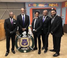 four men in suits and ties standing next to each other with a shield on it