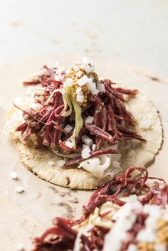 two tortillas topped with shredded red cabbage and white onions on a wooden surface