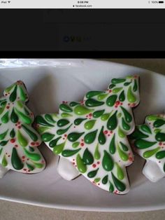 three decorated cookies in the shape of christmas trees