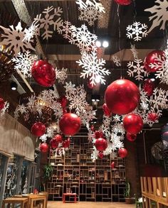 red and white christmas decorations hanging from the ceiling in a store with snowflakes