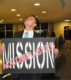 a man is holding a sign that says accomplished in front of him