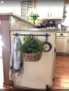 a potted plant sitting on top of a kitchen counter next to a clock and towel rack