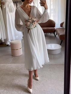 a woman taking a selfie while wearing a white dress