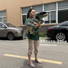 a woman holding a large alligator in her arms while standing next to a parking lot