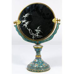 an ornate mirror with blue and gold trimmings on the sides, decorated with bamboo branches