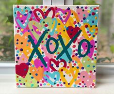 a colorful painting with the word xoxo painted on it in front of a window