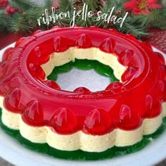 a red and white cake sitting on top of a plate next to a christmas tree