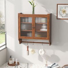 a wooden cabinet hanging on the wall above a sink in a room with white walls