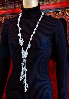 a mannequin wearing a black sweater and white necklace