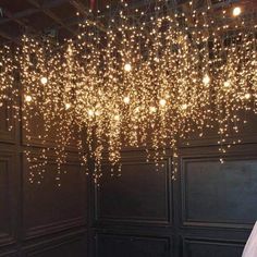 some lights that are hanging from the ceiling in front of a room with black walls