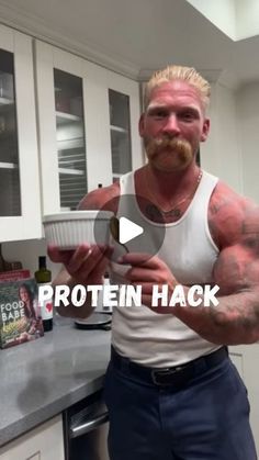 a man in a kitchen holding a bowl with his arm and chest covered in tattoos