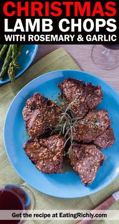 christmas lamb chops with rosemary and garlic on a blue plate next to wine glasses