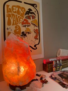 an orange rock sitting on top of a table next to other rocks and crystals in front of a poster