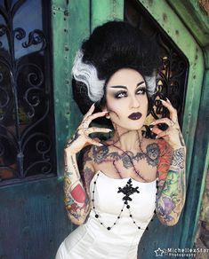 a woman in white dress with tattoos on her body and hands behind her head posing for the camera