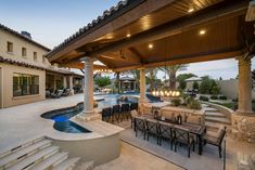 an outdoor dining area next to a swimming pool and covered patio with lights on the ceiling